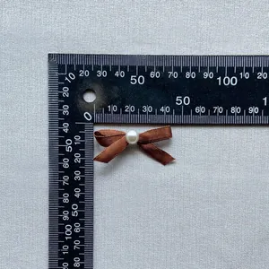 Brown satin bow ornament with white pearl center and 35mm measurement scale display