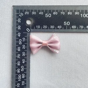 Detalle de lazo de satén rosa con patrón de purpurina plateada sobre tela gris