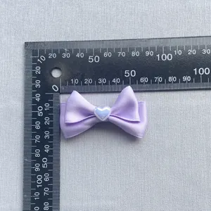 Dettaglio di un fiocco in raso viola da 45mm con cuore bianco e scala di misurazione
