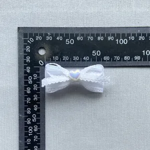 Detailopname van witte DIY kanten strik met hartkraal en schaalmeting van de grootte