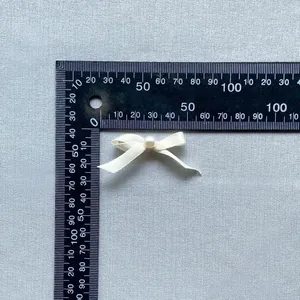Detail shot of a ribbon bow with pearl center next to a ruler for 4cm size reference