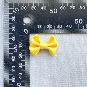 Macro detail of a small yellow satin bow accessory with scale ruler measurement