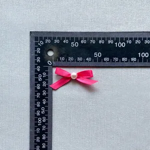 Macro detail of a 35mm pink ribbon bow with a center pearl for DIY cake decoration
