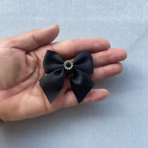 Close-up of small black grosgrain ribbon bow with a crystal center on a hand palm