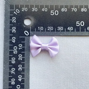 Macro view of a 25mm lilac satin ribbon bow on a scale for size reference