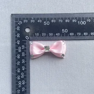 Macro view of pink satin bow with rhinestones and ruler measuring the 40mm length