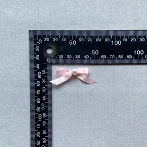 Detailed macro view of a pink satin bow with a central pearl pearl for cake decoration