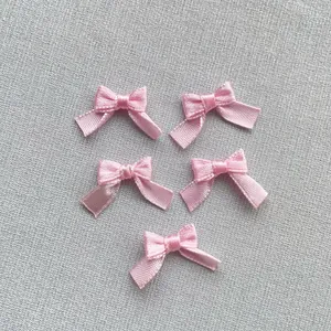Detalle de cinco mini lazos de satén rosa para arte de uñas y ropa de muñecas