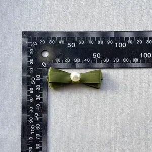 Detalle de lazo de satén verde oliva con perla blanca para decoración de botellas