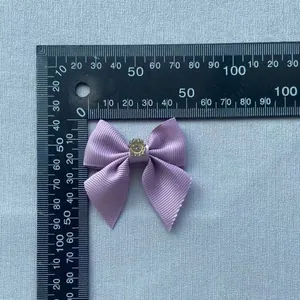 Detail showing a 4cm purple grosgrain ribbon bow with centered rhinestone and ruler