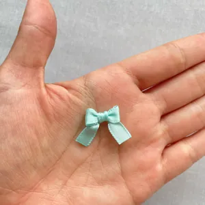 Primer plano de un mini lazo de cinta azul claro en la mano mostrando su tamaño de 1,5 cm
