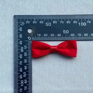Detailed view of a red handmade satin bow showing size measurement with a ruler
