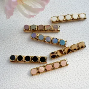 Dettaglio di ciondoli modulari italiani colorati su bracciali in acciaio dorato