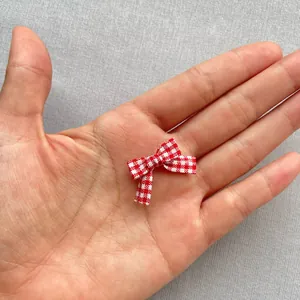 Primer plano detallado de mini lazos de cuadros rojos y blancos de 1,5 cm en la palma