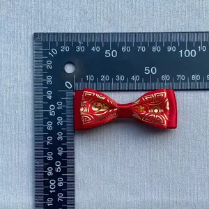 Macro view of a 50mm handmade red satin bow with golden Chinese cloud patterns and ruler scale
