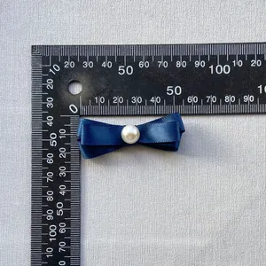 Detalle de un lazo de satén azul marino de 40 mm con perla para decoración DIY