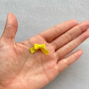 Vista de cerca de mini lazo de satén amarillo de 1,5 cm para manualidades en una palma
