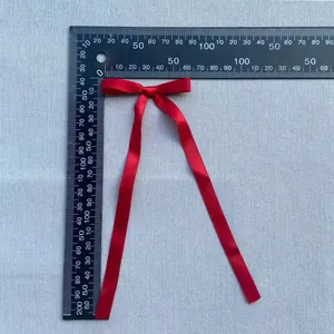 Detailed size measurement of a red satin ribbon bow accessory with long hanging streamers