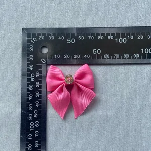 Macro detail of a pink grosgrain bow accessory with rhinestone center measuring 40mm wide