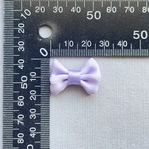 Macro detail of 3cm lavender satin bow ornament measured on a black metal scale