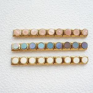 Dettaglio di tre bracciali charm italiani con base dorata e inserti in conchiglia colorata