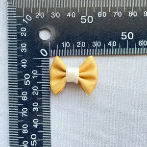 Macro shot showing size measurement of 3cm yellow fabric bow for DIY crafts and decor