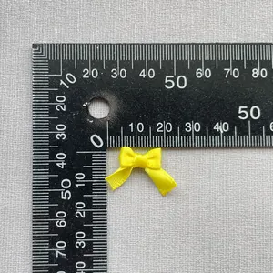 Detalle de lazo de satén amarillo de 15 mm con regla para manualidades y costura