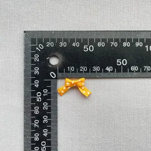 Detalle de un lazo de cinta naranja con lunares de 15 mm mostrado con regla de escala