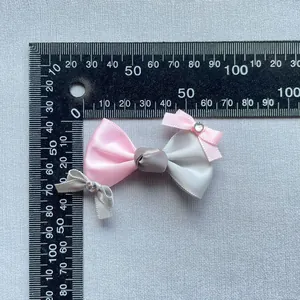 Detailansicht handgefertigte Schleife aus Satin in Rosa und Grau mit Strass auf Lineal