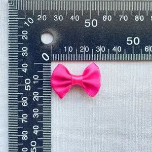 Macro shot of a 3cm hot pink satin bow with a ruler for DIY craft size reference