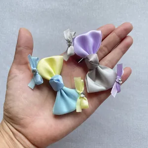 Detailansicht von drei handgefertigten Satin-Schleifen mit Glitzersteinen in einer Hand