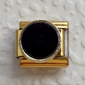Vista macro di un charm italiano modulare dorato con un inserto centrale in smalto nero