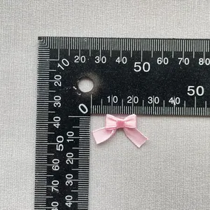 Vista detallada de un lazo de satén rosa claro de 1,5 cm para manualidades con regla