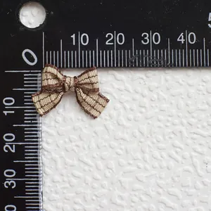 Vista detallada de un mini lazo a cuadros marrón con regla de medición para accesorios DIY