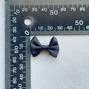 Detailed view of a 3cm black satin bow accessory measured with a precision scale ruler