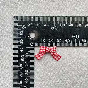 Primer plano de un mini lazo de tela a cuadros rojos y blancos con regla para medir talla