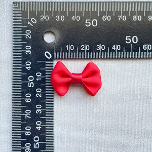 Detailed macro view showing the size and texture of a 3cm red satin DIY bow accessory