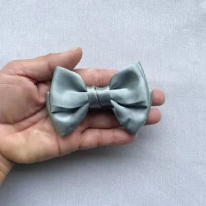 Detailed view of a hand-held light blue satin double layered bow for hair and garment deco