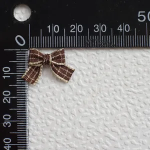 Vista macro de un mini lazo de cuadros marrón que muestra el tamaño de 18mm en regla