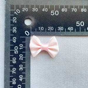 Macro view of a 3cm baby pink satin ribbon bow accessory with a measuring scale
