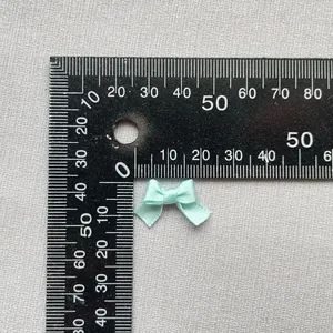 Detalle macro de un lazo de satén verde menta de 1,5cm mostrando textura y escala real