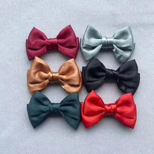 Flat lay of satin double bows in six colors including red, black, and emerald green