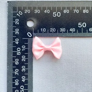Macro detail of a 25mm pink satin ribbon bow accessory with measurement scale