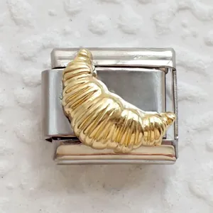 Macro shot of a stainless steel Italian charm link featuring a golden croissant motif