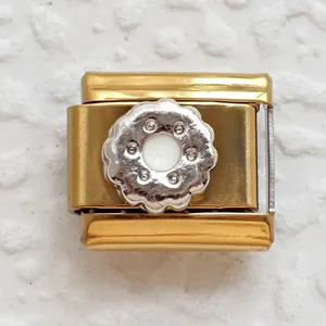 Macro detail of Italian charm bracelet link with gold base and silver flower accent
