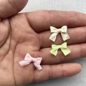 Dettaglio di fiocchi fatti a mano in poliestere da 1,5 cm in rosa, verde e bianco crema