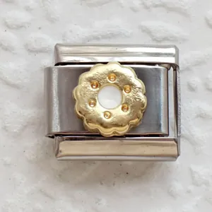 Detail of stainless steel Italian charm featuring a gold floral circular inlay