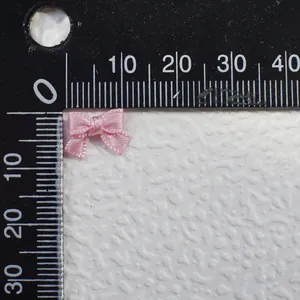 Detail showing 10mm mini pink satin ribbon bow with ruler scale for size reference