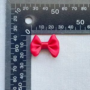 Detail view of a 3cm red satin bow showing material texture and size scale measurement