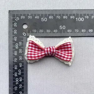 Detail of red gingham plaid fabric bow with lace trim showing 5cm size on a scale
